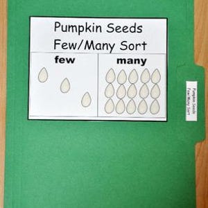 May include: A green file folder with a white paper insert labeled "Pumpkin Seeds Few/Many Sort." The insert shows a few pumpkin seed illustrations in the "few" section and many in the "many" section. A smaller label on the folder's tab repeats the title.