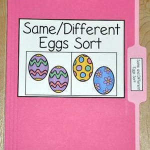 May include: A pink file folder with a label that reads "Same/Different Eggs Sort." The label features four colorful Easter egg illustrations. A smaller label on the tab also reads "Same and Different Eggs Sort."