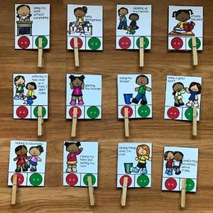 May include: A set of twelve educational cards with illustrations and text, each attached to a wooden clothespin. The cards feature various scenarios with corresponding red and green buttons, designed for interactive learning and behavioral guidance.