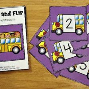 May include: Educational flashcards featuring a school bus design. The flipbook cover says "Match and Flip Count the Students." Individual cards display numbers 1-5 alongside school bus illustrations. The cards are purple with a yellow school bus.
