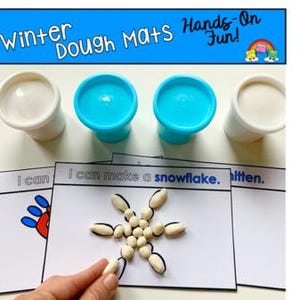May include: Winter-themed dough mats with the text "Winter Dough Mats Hands-On Fun!". The image displays white and blue dough containers, and printed cards. One card features a snowflake constructed from small objects.