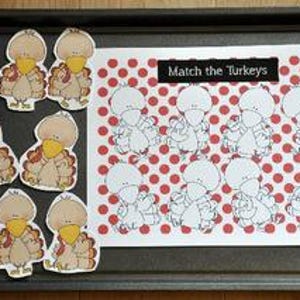 May include: A black baking tray displays a matching game. The game includes turkey cutouts and a card with a red polka dot pattern and turkey outlines. The text "Match the Turkeys" is on the card.