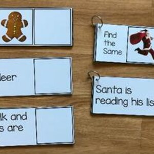 May include: A set of white flashcards with metal rings, featuring Christmas-themed text and images. The cards include phrases like "Find the Same," "reindeer," and "Santa is reading his list." A gingerbread man and Santa Claus are also depicted.