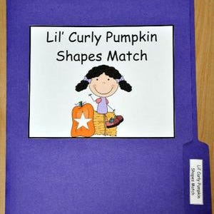 以下が含まれることがあります： 紫色のファイルフォルダー。白い長方形に「Lil' Curly Pumpkin Shapes Match」の文字、女の子、カボチャ、干し草の束の漫画イラストが描かれています。フォルダーのタブにはタイトルが記載されたラベルが付いています。