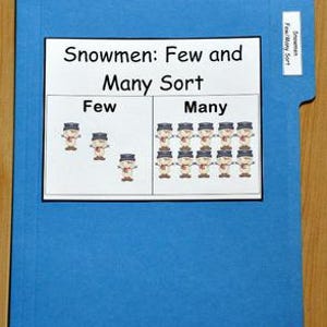 May include: A blue file folder with a white label that reads "Snowmen Few/Many Sort." The folder contains a printed page with the title "Snowmen: Few and Many Sort." The page shows a few snowmen on the left and many snowmen on the right.
