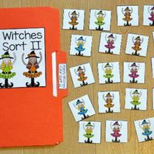Op de afbeelding: Een oranje map met de tekst "Happy Witches Color Sort II" en illustraties van heksen. Kleine vierkante kaarten met heksenafbeeldingen liggen verspreid op een houten oppervlak.