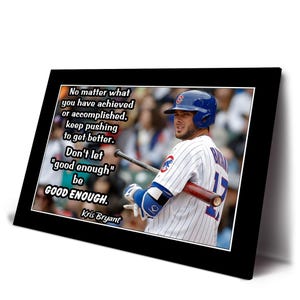 以下が含まれることがあります： 青と白のユニフォームを着てバットを持った野球選手の額装プリント。プリントには、クリス・ブライアントによる「No matter what you have achieved...be GOOD ENOUGH.」というテキストが含まれています。フレームは黒です。
