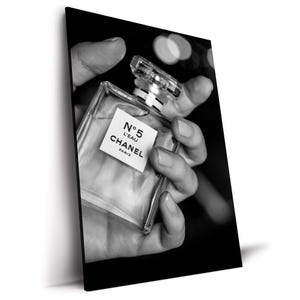 Puede incluir: Un frasco de perfume de cristal transparente con forma cuadrada y tap&oacute;n transl&uacute;cido. La etiqueta presenta el texto N&deg;5 L'EAU CHANEL PARIS en letras negras. El frasco aparece en una fotograf&iacute;a en blanco y negro de alto contraste.