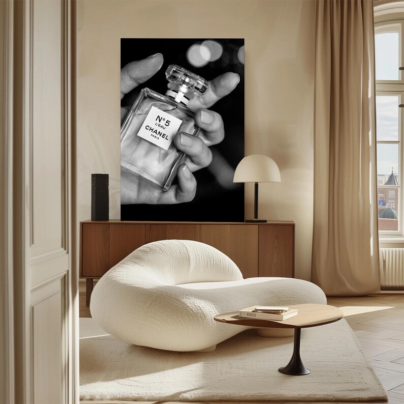 Puede incluir: Un gran cuadro rectangular de pared con una fotograf&iacute;a en blanco y negro de un frasco de perfume de cristal con la etiqueta N&deg;5 L'EAU CHANEL PARIS. La imagen muestra el frasco sostenido en una mano sobre un fondo oscuro con c&iacute;rculos de luz.