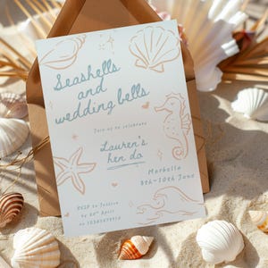 Peut inclure: Une invitation bleu clair et p&ecirc;che avec le texte "Seashells and wedding bells" et "Lauren's hen do". L'invitation pr&eacute;sente des illustrations de coquillages et d'hippocampes. L'invitation est entour&eacute;e de coquillages sur une surface sablonneuse.