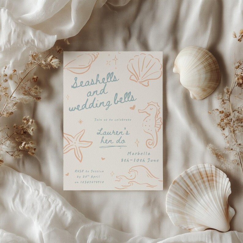 Peut inclure: Une invitation de mariage avec le texte "Seashells and wedding bells" en &eacute;criture bleu clair, avec des illustrations de coquillages et d'hippocampes. L'invitation est entour&eacute;e de coquillages et de fleurs s&eacute;ch&eacute;es, sur un fond de tissu blanc.