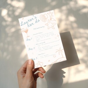 Peut inclure: Une carte d'itin&eacute;raire de couleur claire avec le texte "Lauren's hen do" et "Itin&eacute;raire" dans un style manuscrit. La carte pr&eacute;sente des illustrations d'un cocktail, de coquillages et d'un palmier. L'itin&eacute;raire d&eacute;taille les activit&eacute;s sur trois jours.