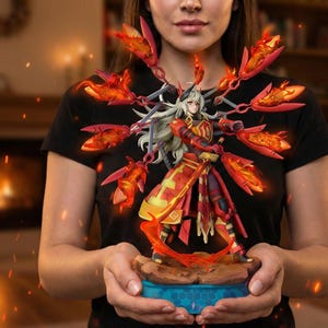 May include: A detailed figurine of a character with white hair and a red and gold outfit, surrounded by fiery, wing-like elements. The figure is held in front of a person wearing a black t-shirt. The base is blue and brown.