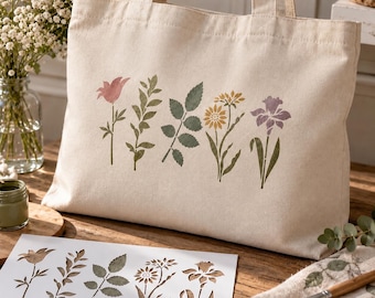 May include: A cream-colored canvas tote bag featuring a printed design of five distinct botanical elements including flowers and leaves in muted shades of pink, green, yellow, and purple, accompanied by a matching stencil sheet.