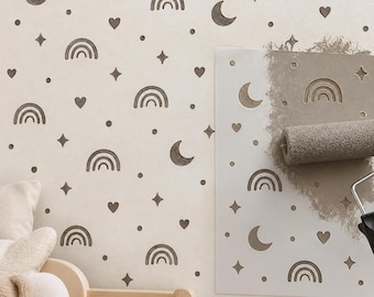 May include: A wall stencil featuring a repeating pattern of rainbows, crescent moons, hearts, stars, and dots. A paint roller is applying grey paint over the stencil onto a wall, revealing the design in grey against a light background.