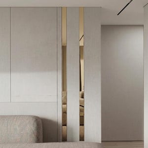 May include: A wall paneling system featuring light gray, textured vertical panels separated by two narrow, reflective gold-toned metallic strips that create a vertical accent. The design includes a section of a light gray upholstered sofa.