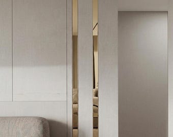 May include: A wall paneling system featuring light gray, textured vertical panels separated by two narrow, reflective gold-toned metallic strips that create a vertical accent. The design includes a section of a light gray upholstered sofa.