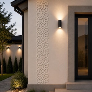 May include: A beige exterior wall featuring a vertical relief panel with a geometric maze pattern. A cylindrical black wall sconce is mounted to the right of the panel, emitting a warm light that casts upward and downward beams onto the wall surface.