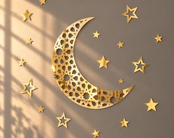 May include: A gold-colored wall decal set featuring a large crescent moon with an intricate geometric cutout pattern, accompanied by various sizes of solid and open-frame star shapes arranged around the central moon piece.