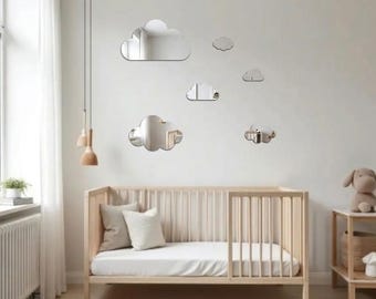 May include: A set of five cloud-shaped wall mirrors in varying sizes, featuring reflective surfaces with smooth, rounded edges. These decorative mirrors are arranged in a cluster on the wall above a wooden crib, creating a clear, reflective display.