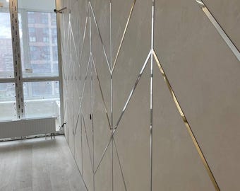 May include: A wall paneling system featuring large, matte beige rectangular panels arranged in a geometric pattern. The panels are separated by thin, reflective silver metal strips that create a continuous zigzag and diamond design across the surface.
