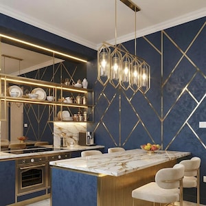 May include: A rectangular gold metal chandelier with five vertical glass cylindrical shades hangs above a kitchen island. The island features a white marble countertop with gold veining and a gold fluted base, paired with cream-colored chairs.