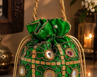 May include: A vibrant green drawstring handbag featuring a satin-like finish, adorned with circular mirrors and intricate gold-toned metallic embroidery. The bag includes a braided gold handle and matching gold drawstring cords with tassel ends.