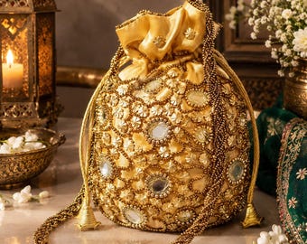 May include: A gold drawstring pouch bag featuring an intricate exterior adorned with metallic beadwork, small floral-shaped sequins, and circular mirror accents. The bag includes a long, braided beaded strap and a gathered top closure with tassels.