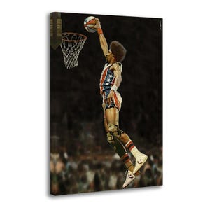May include: A canvas print of a basketball player in mid-air, about to dunk the ball. The player wears a red, white, and blue uniform with stars. The basketball is orange, white, and blue. The background is dark with a crowd.