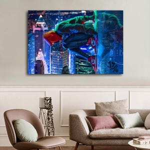 Puede incluir: Un lienzo que presenta a un superh&eacute;roe con un traje verde y negro, zapatos rojos y una capucha naranja, aferrado a un rascacielos. El fondo muestra un vibrante paisaje urbano nocturno, con luces azules y blancas brillantes que iluminan los edificios.