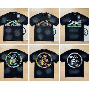 以下が含まれることがあります： さまざまな配色で「HELLSTAR」ロゴがプリントされた黒いTシャツ6枚。Tシャツの前面にはロゴとテキストが、背面には顔と炎の円形デザインが施されています。Tシャツは色あせ、ダメージ加工が施されています。