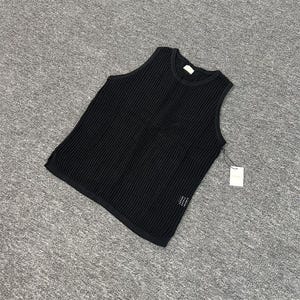 May include: A black sleeveless knit top with a textured, ribbed design. The top has a round neckline and a tag attached. The fabric appears to be a medium weight, suitable for layering or warmer weather.