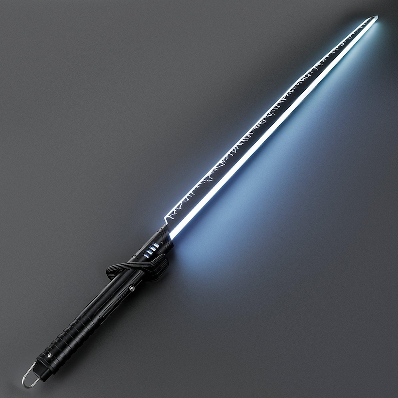 Op de afbeelding: Een zwart lichtzwaard met een gloeiend wit en blauw lemmet. Het lemmet heeft ge&euml;tste ontwerpen langs de rand. Het handvat is zwart met een getextureerde grip en een lus aan het uiteinde. Het lichtzwaard staat tegen een grijze achtergrond.