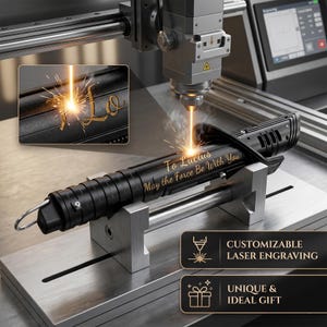 Op de afbeelding: Zwart lichtzwaard met lasergravure. De tekst "To Lucius May the Force Be With You" is gegraveerd op het lichtzwaard. De afbeelding toont ook de woorden "CUSTOMIZABLE LASER ENGRAVING" en "UNIQUE & IDEAL GIFT".