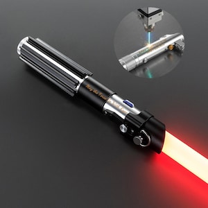 May include: A black and silver lightsaber with a red blade. The hilt has a ribbed design and the text "May the Force Be With Ryan" is engraved on the side. A smaller, similar lightsaber is being laser engraved with the same text.