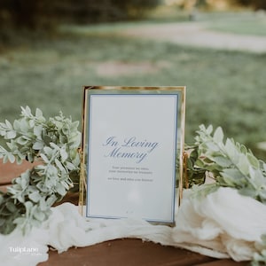Può includere: Un cartello con cornice dorata con la scritta "In Loving Memory" in elegante corsivo. Il cartello ha uno sfondo bianco con bordi blu. Il testo include le frasi "Your presence we miss" e "we love and miss you forever."