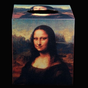 May include: A wooden tissue box cover with a printed image of the Mona Lisa painting. The box is a square shape with a cutout for tissues.