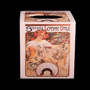 May include: A white tissue box cover with a vintage art nouveau design featuring a woman in a white dress holding a plate of biscuits. The text "Biscuits Lefèvre-Utile" and "1897" are printed on the box.