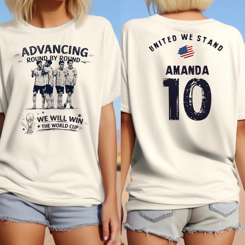 May include: White t-shirt with a soccer-themed graphic. The front features a team illustration and text: "ADVANCING ROUND BY ROUND" and "WE WILL WIN THE WORLD CUP." The back displays "UNITED WE STAND," the name "AMANDA," and the number "10."
