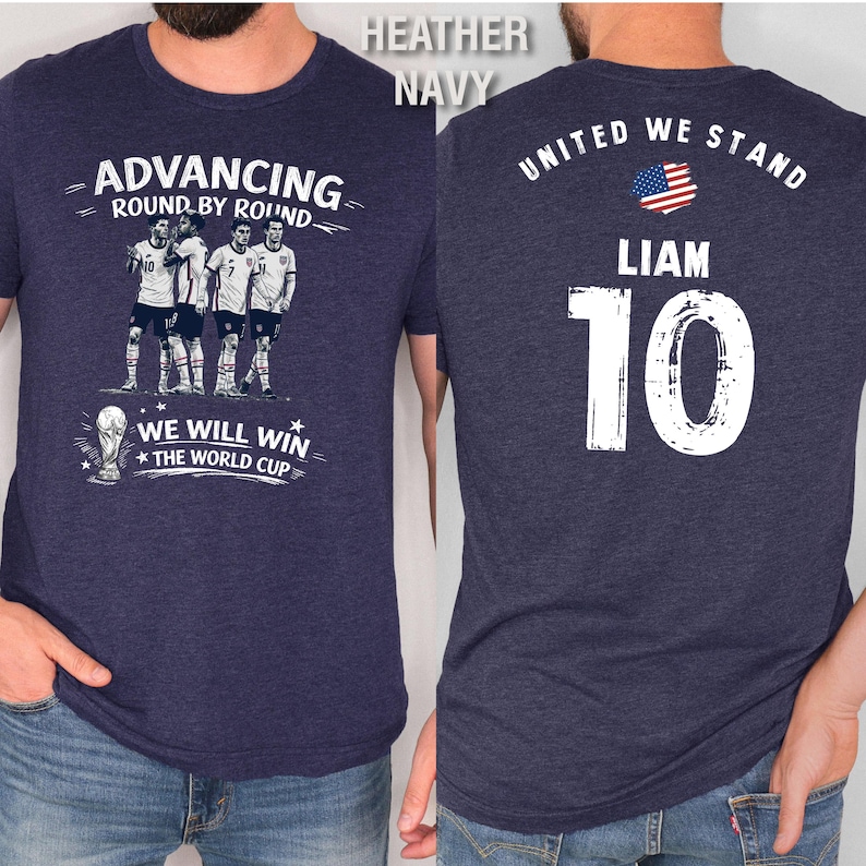 May include: Heather navy t-shirt with a soccer team graphic on the front and the text "ADVANCING ROUND BY ROUND" and "WE WILL WIN THE WORLD CUP". The back of the shirt has the text "UNITED WE STAND", the name "LIAM", and the number "10".
