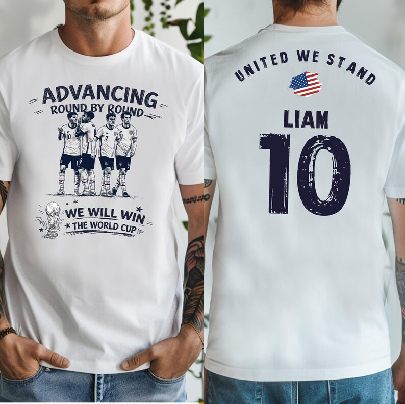 May include: White t-shirt with a soccer-themed design. The front features a graphic of soccer players and the text "ADVANCING ROUND BY ROUND" and "WE WILL WIN THE WORLD CUP". The back displays "UNITED WE STAND", the name "LIAM", and the number "10".
