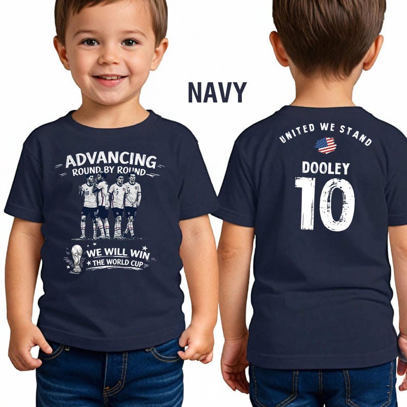 May include: Navy blue youth t-shirt with the text "ADVANCING ROUND BY ROUND" and "WE WILL WIN THE WORLD CUP". The back of the shirt displays "UNITED WE STAND", the name "DOOLEY", and the number "10".