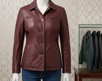 Puede incluir: Chaqueta de cuero burdeos con cuello y cierre de tres botones. La chaqueta tiene dos pequeños bolsillos en el pecho y un corte entallado. Otras chaquetas de diferentes colores cuelgan en un perchero en el fondo.