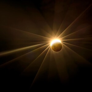 Könnte beinhalten: Eine künstlerische Darstellung eines Himmelsereignisses. Eine helle, goldene Sonne bricht mit strahlenden Lichtstrahlen vor einem dunklen Hintergrund hervor. Eine teilweise beleuchtete Kugel ist sichtbar, was auf eine Sonnenfinsternis oder ein ähnliches Phänomen hindeutet.
