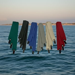 May include: A white ceramic mug with a black handle and the text "But First, Coffee" in a bold, black font. The mug is set against a blurred background, suggesting a cozy setting.