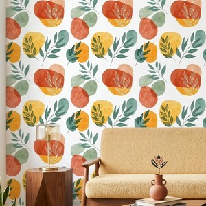 Könnte beinhalten: Ein Raum mit einem gelben Sofa, Holzmöbeln und einer gemusterten Tapete. Die Tapete hat ein sich wiederholendes Design aus abstrakten Formen in Orange, Gelb und Grün auf weißem Hintergrund. Ein grünes Kissen liegt auf dem Sofa.