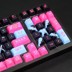 May include: A black mechanical keyboard with custom keycaps. The keycaps are a mix of black, pink, and light blue, with various symbols and text. Some keys have a cloud-like design, while others feature icons and numbers. The keyboard is on a dark surface.