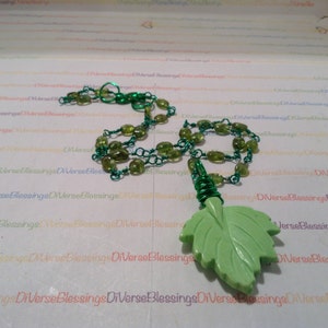 May include: A green gemstone necklace with a green leaf pendant. The necklace is made of green beads and silver chain.