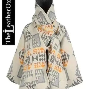 Puede incluir: Una capa con capucha de color crema con un patrón geométrico en gris y naranja. La capa presenta cierres de palanca de madera y el texto "The LeatherOxide" en el lado izquierdo. La capa está diseñada para brindar calidez y estilo.