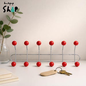 Cabideiro cromado de meados do século XX com ganchos de bola de madeira vermelha, estilo moderno para hall de entrada.